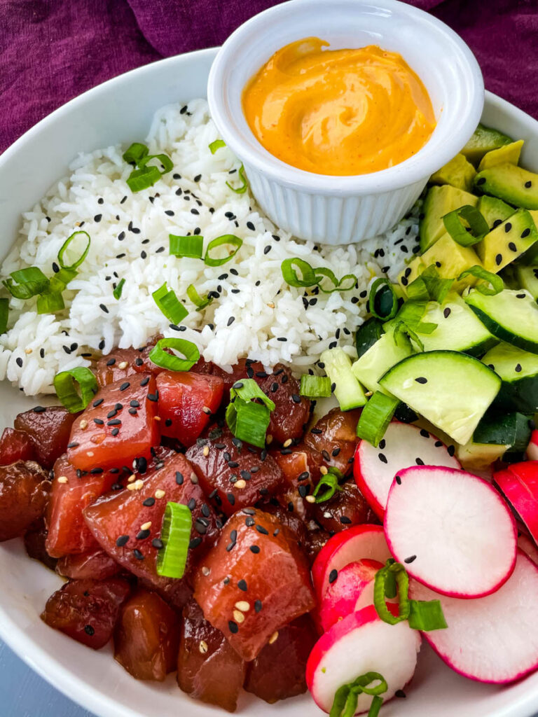 ahi tuna poke bowls with rice, avocado and spicy mayo sauce in a white bowl