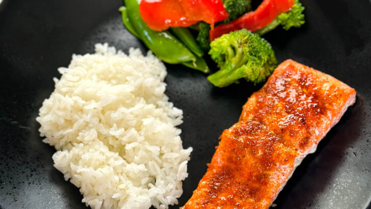 baked salmon, white rice, and vegetables on a black plate
