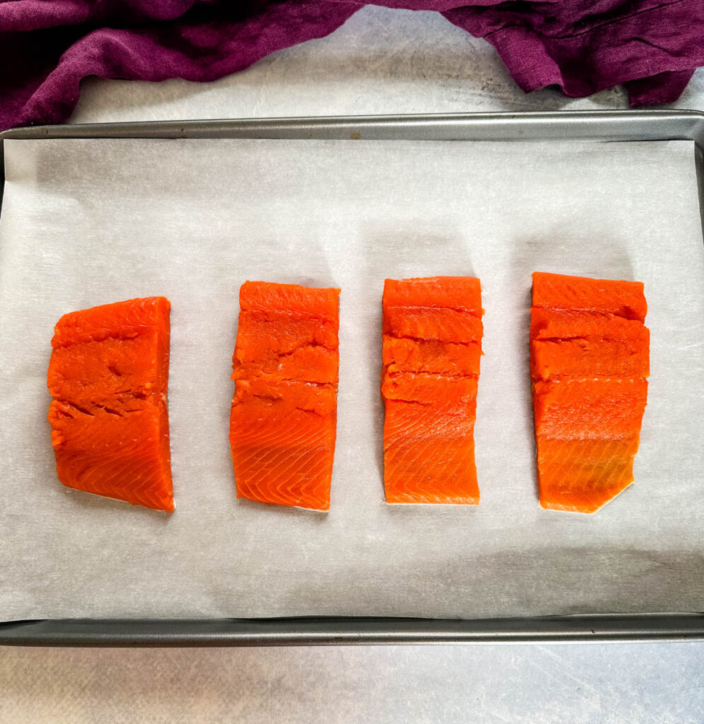 raw salmon on a sheet pan with parchment paper