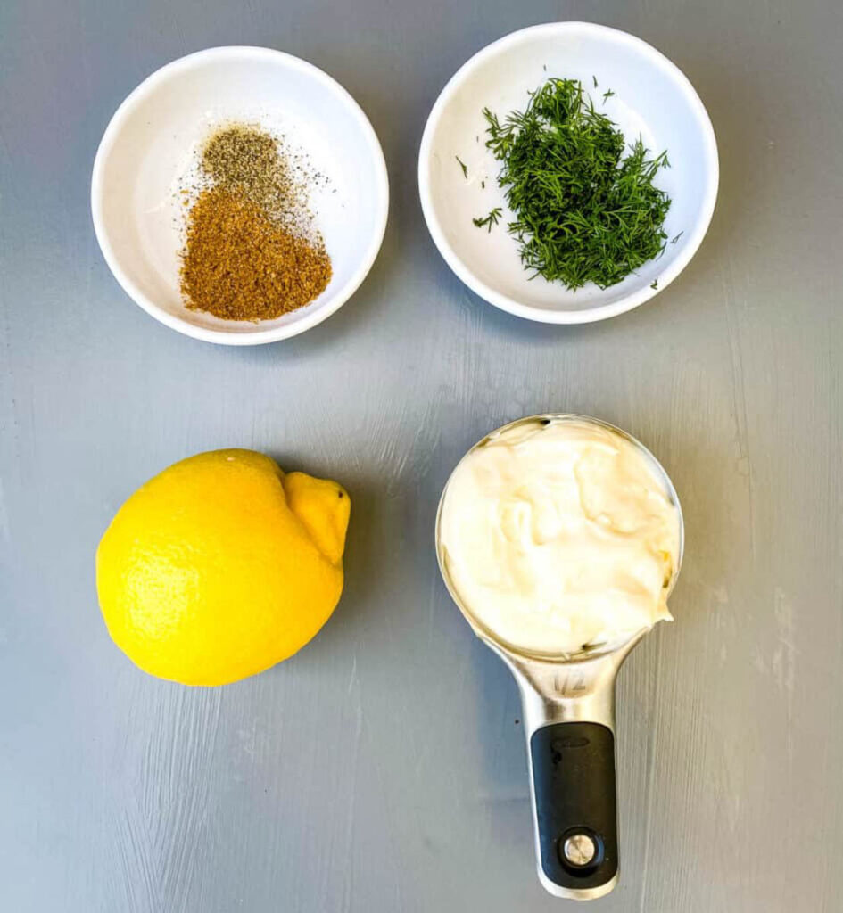 spices, dill, lemon, and mayo on a flat surface