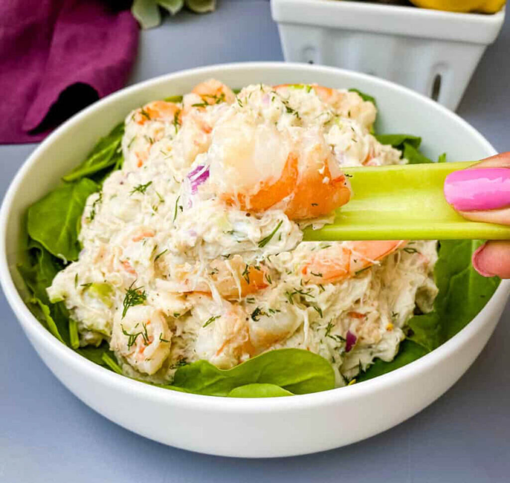person holding crab salad with real lump crab meat on a piece of celery