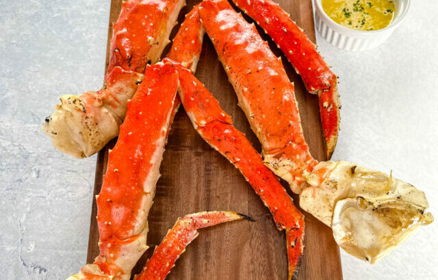 grilled crab legs on a wooden board with fresh lemon and garlic butter