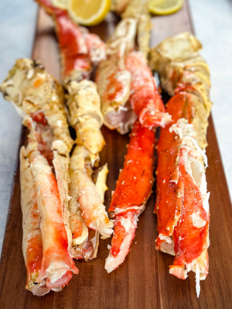 cracked and split king crab legs on a wooden board