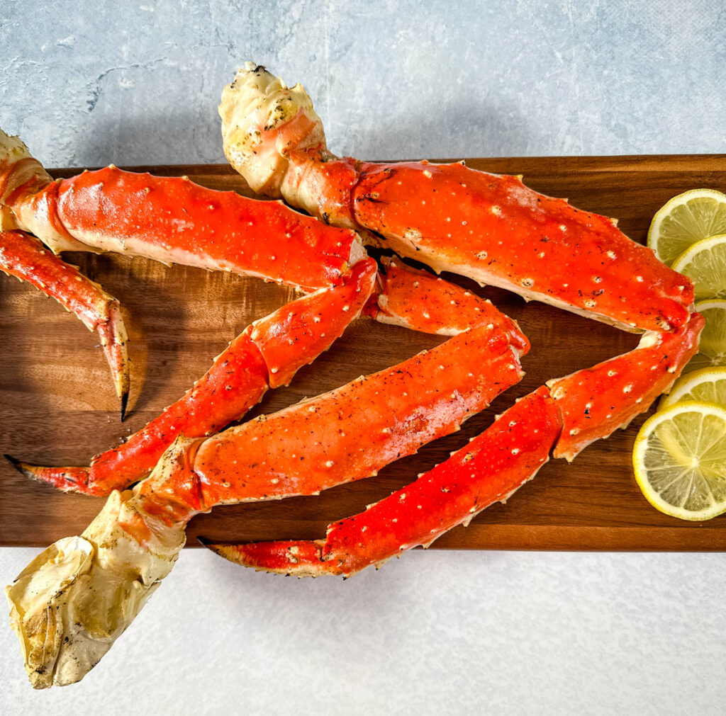 grilled crab legs on a wooden board with fresh lemon