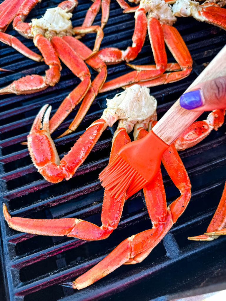 snow crab legs on a grill brushed with butter