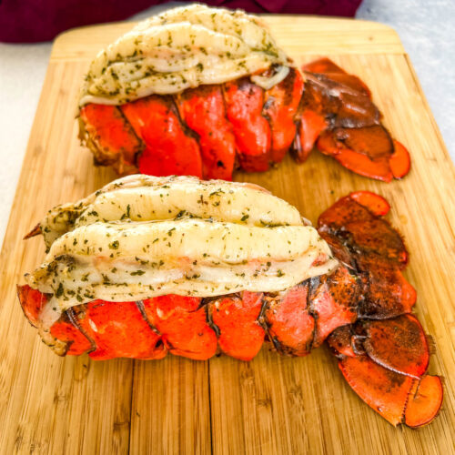 smoked lobster tails with garlic butter on a wooden cutting board