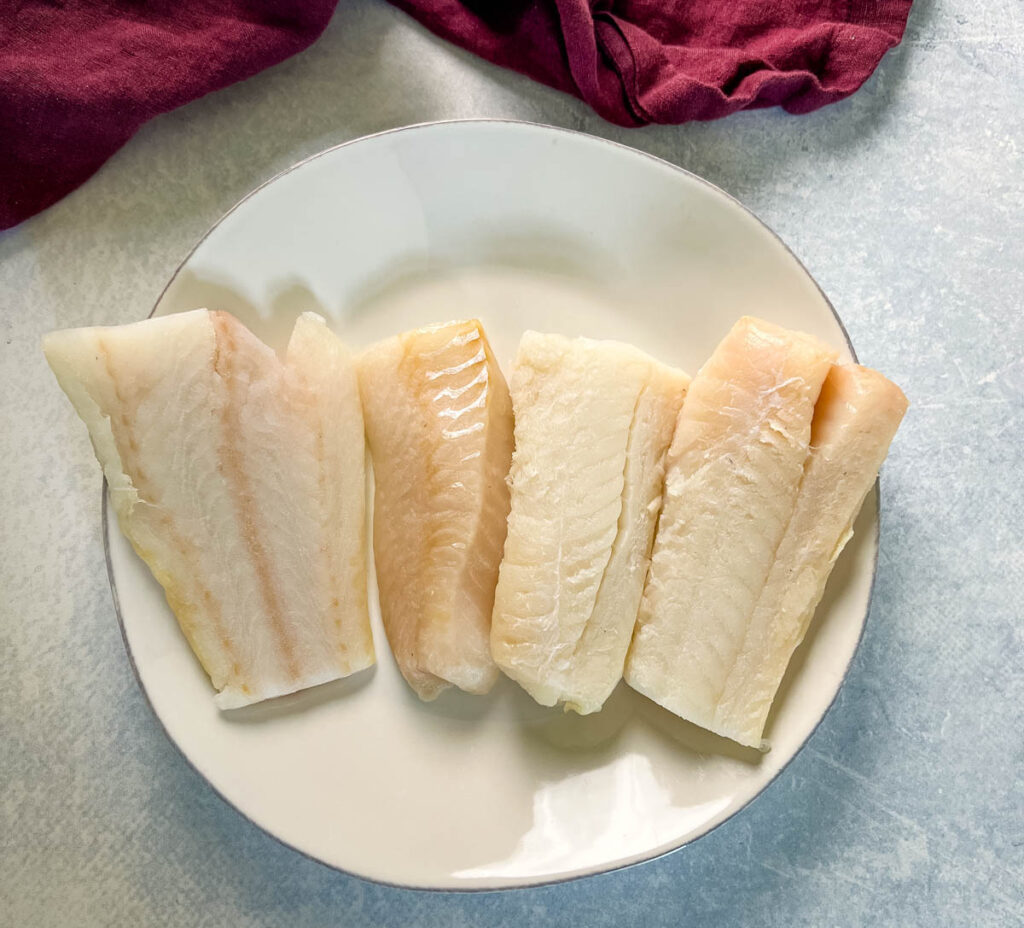 raw cod fillets on a white plate