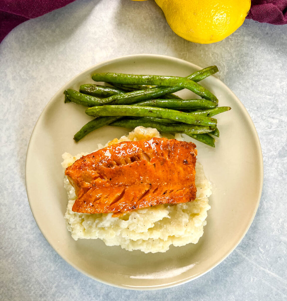 pan seared cod on a plate with mashed potatoes and green beans