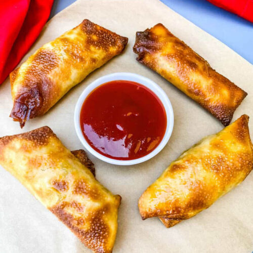 shrimp egg rolls on a flat surface with sweet and sour sauce