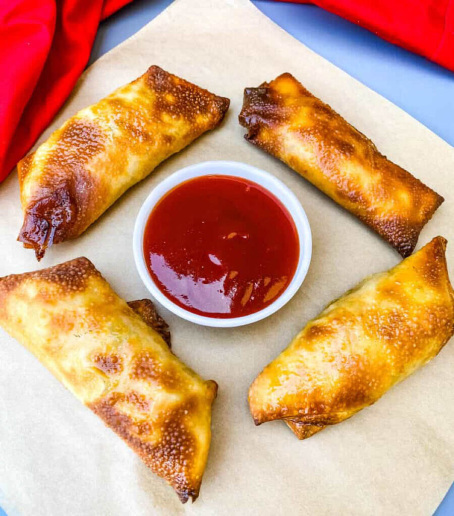shrimp egg rolls on a flat surface with sweet and sour sauce