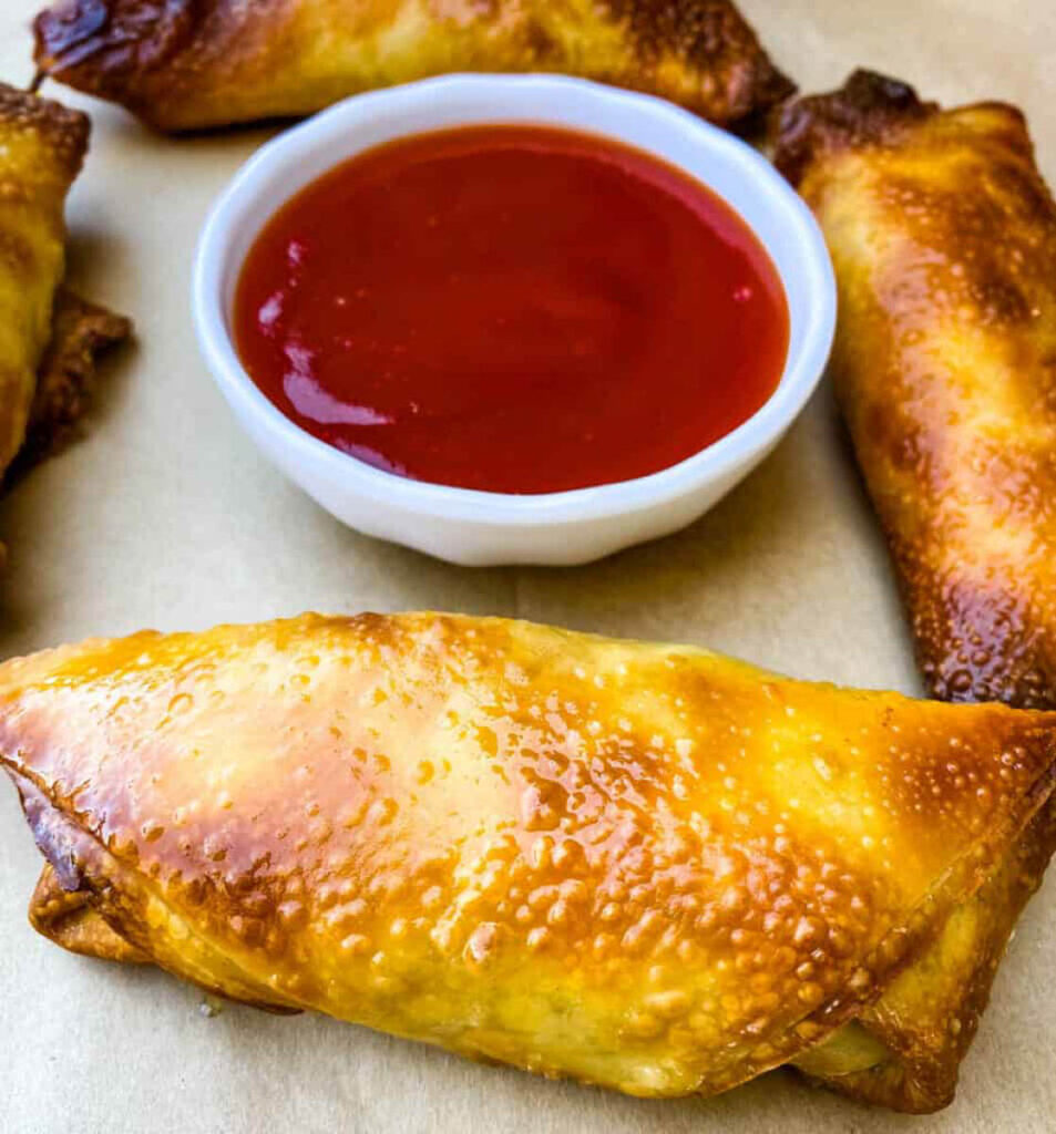 shrimp egg rolls on a flat surface with sweet and sour sauce