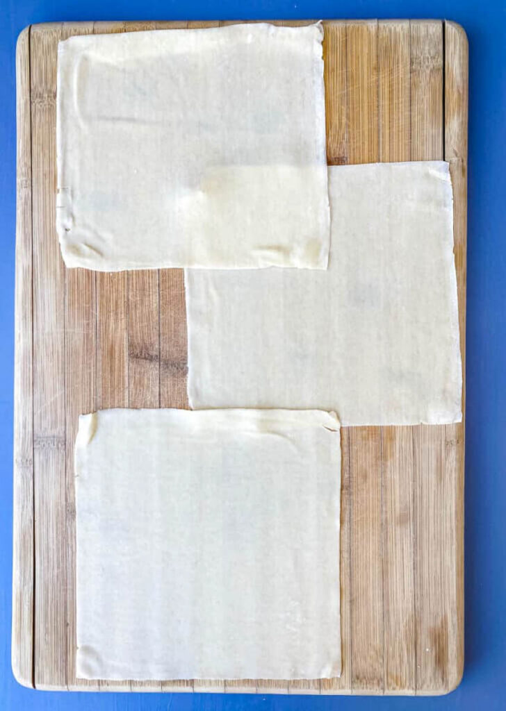 egg roll wrappers on a bamboo cutting board