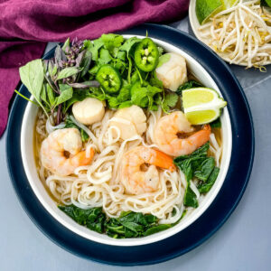 shrimp noodle soup with vegetables and chopsticks in a bowl