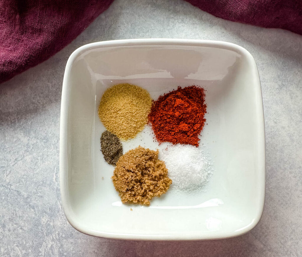 garlic powder, smoked paprika, brown sugar, salt and pepper in a white bowl