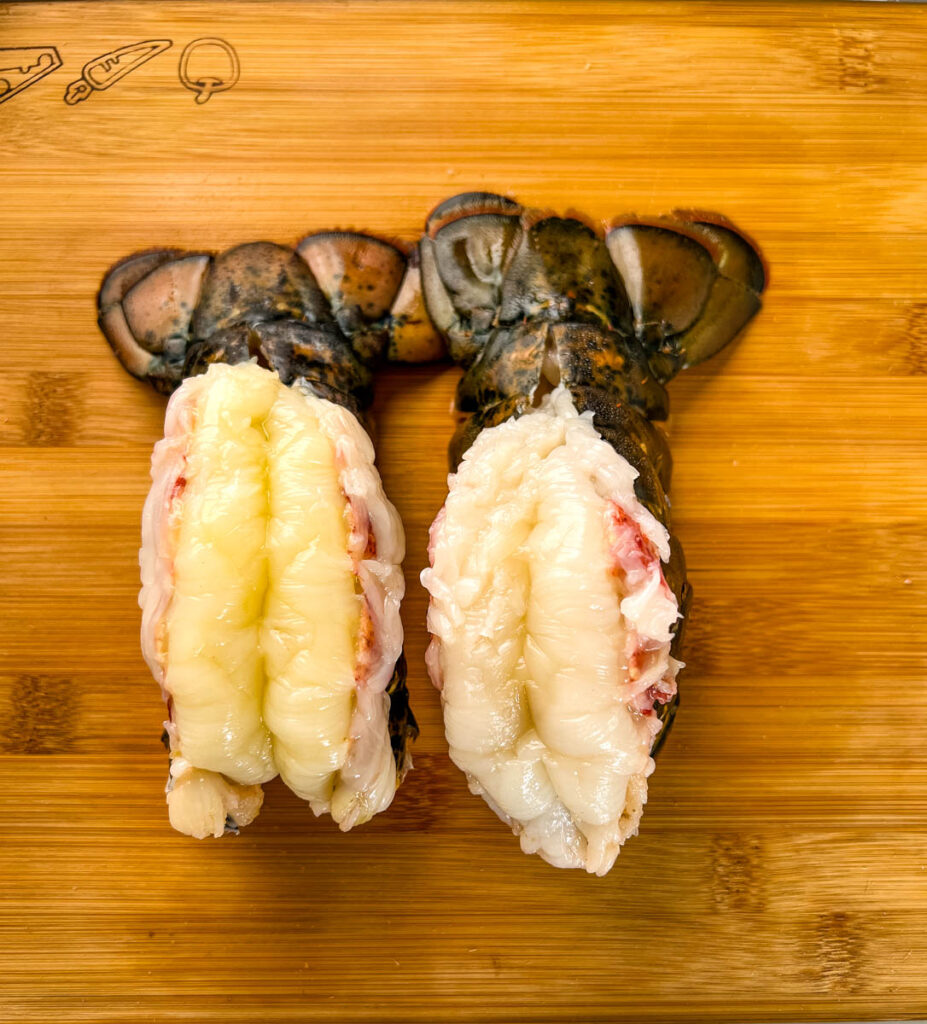 raw butterflied lobster tails on a cutting board