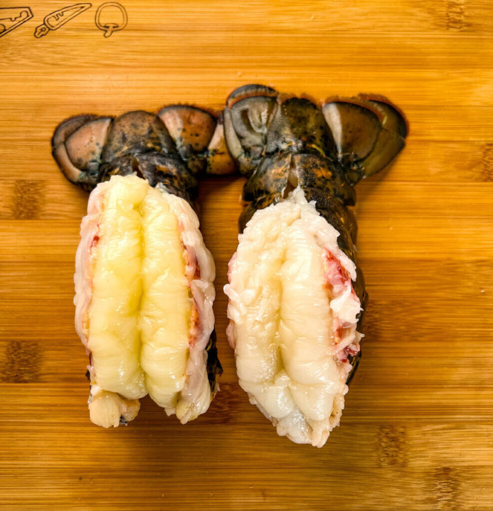 raw butterflied lobster tails on cutting board