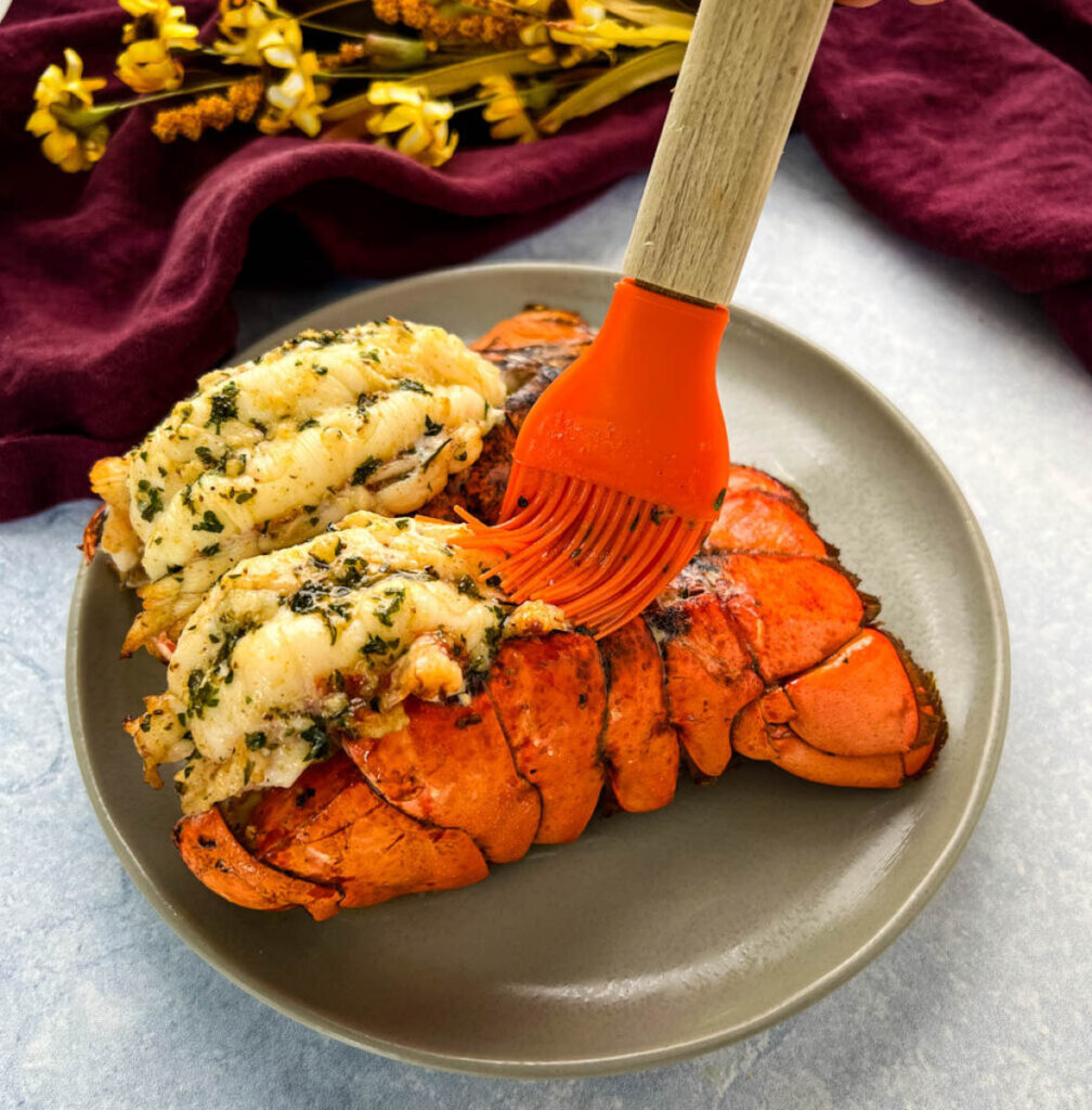 air fryer lobster tail on a plate brushed with lemon garlic butter