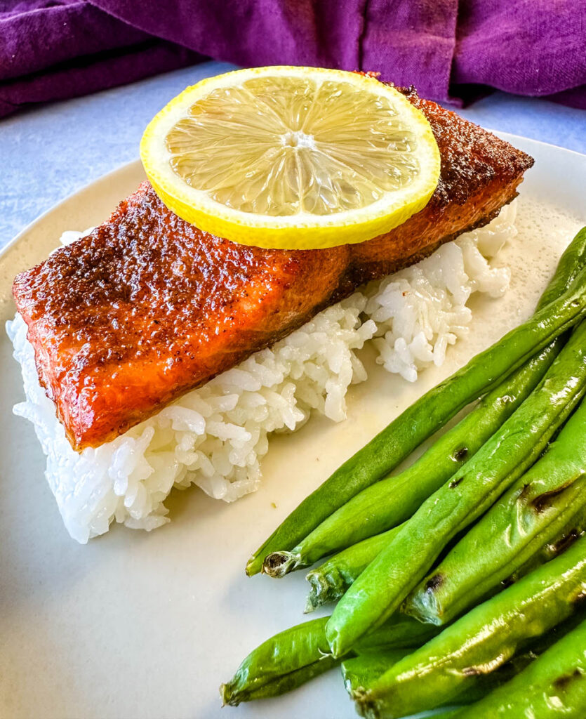 air fryer salmon with fresh lemon, rice, and green beans on a plate