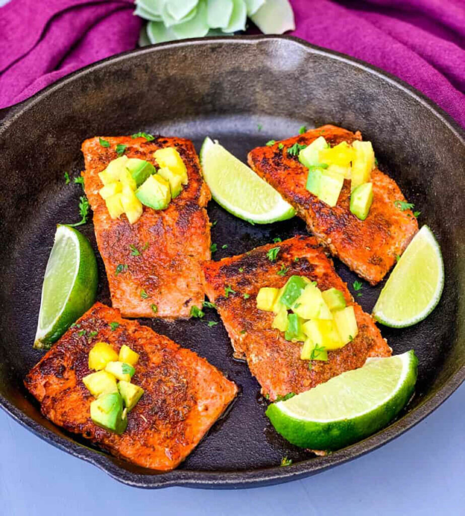 Cajun salmon in a cast iron skillet with mango and lime