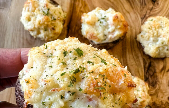 person holding baked seafood stuffed mushroom