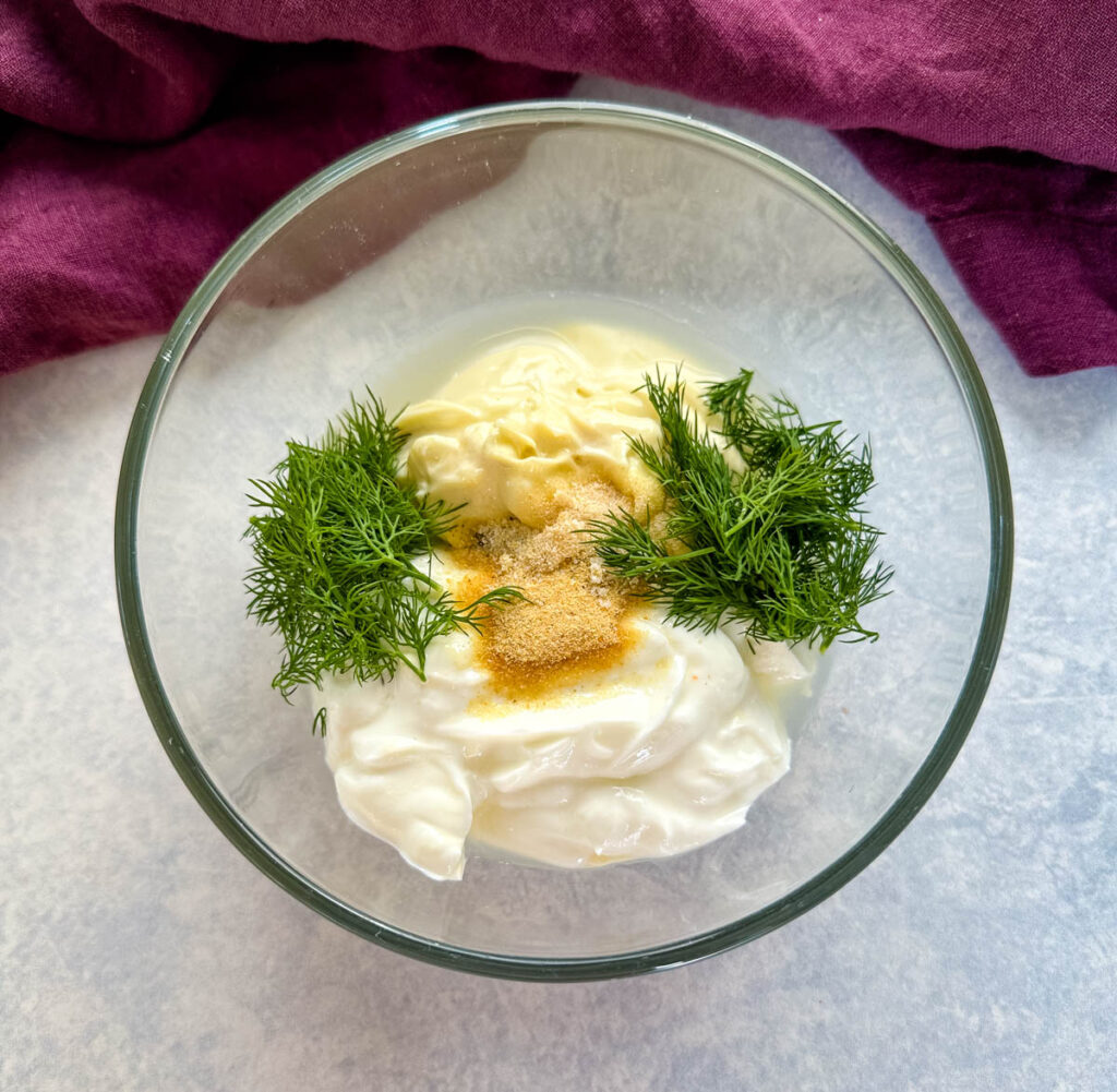 mayo, Greek yogurt, fresh dill, lemon, and herbs in a glass bowl