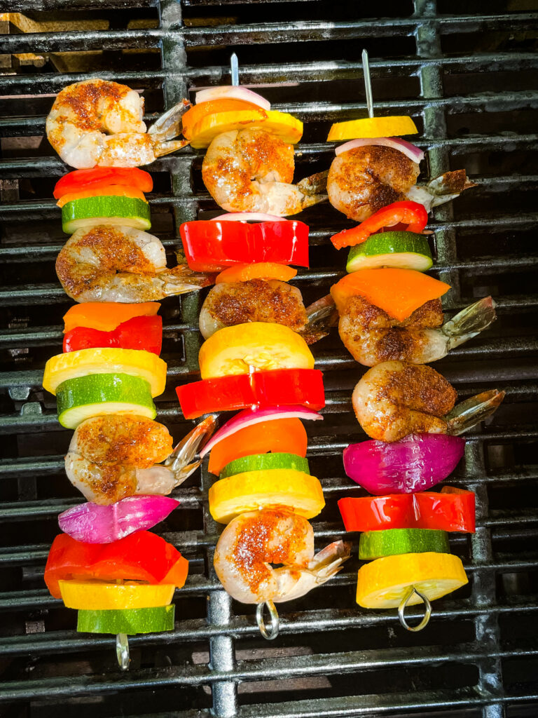 raw shrimp on skewers with vegetables on a grill
