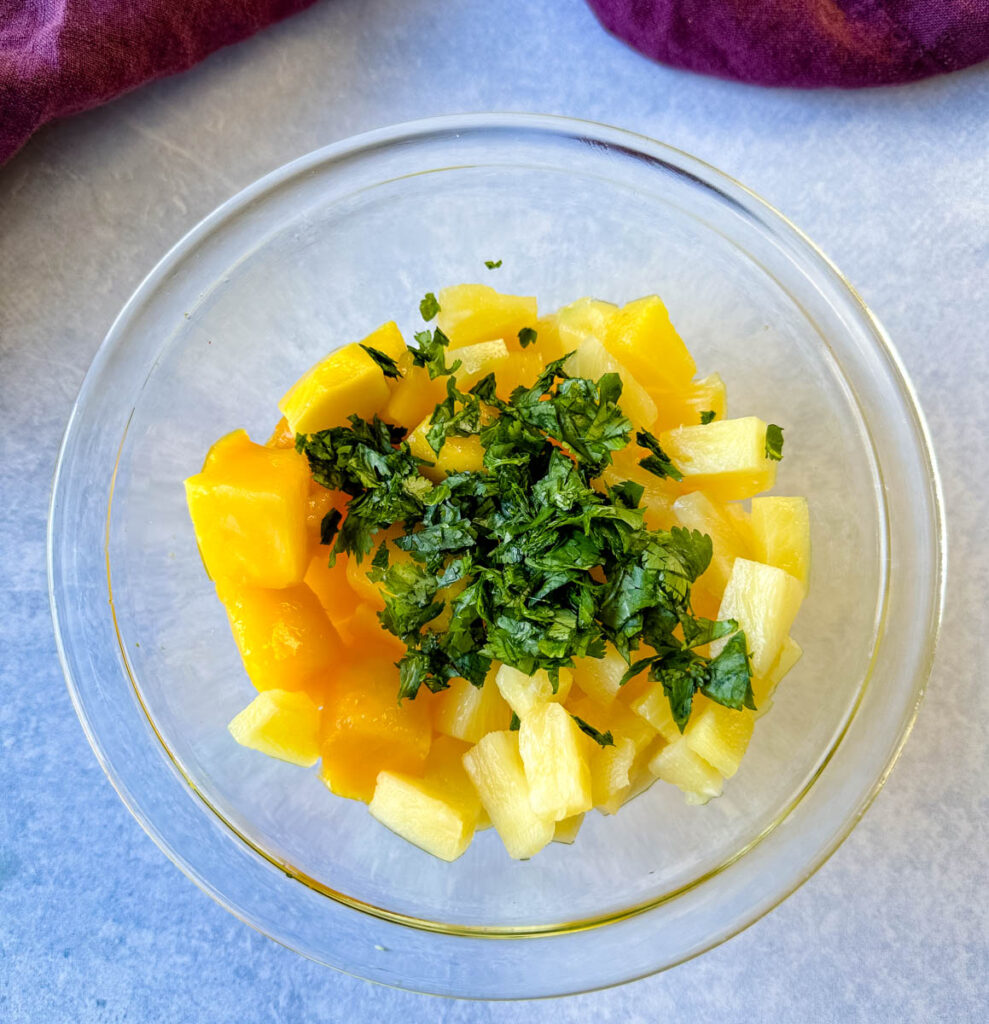 fresh mango, lime, pineapple, and cilantro in a glass bowl