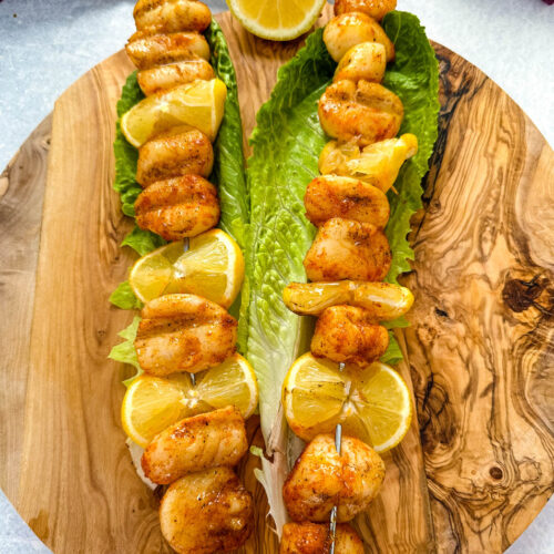 smoked scallops on skewers on a bed of lettuce with lemons