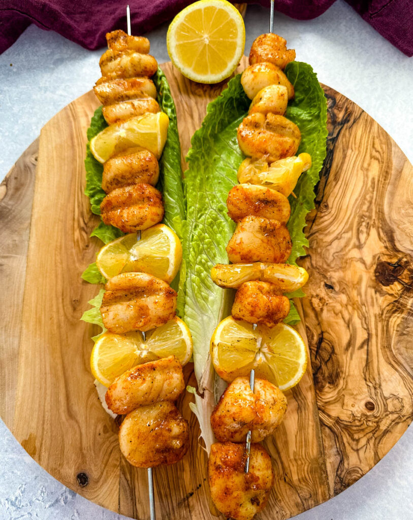 smoked scallops on skewers on a bed of lettuce with lemons