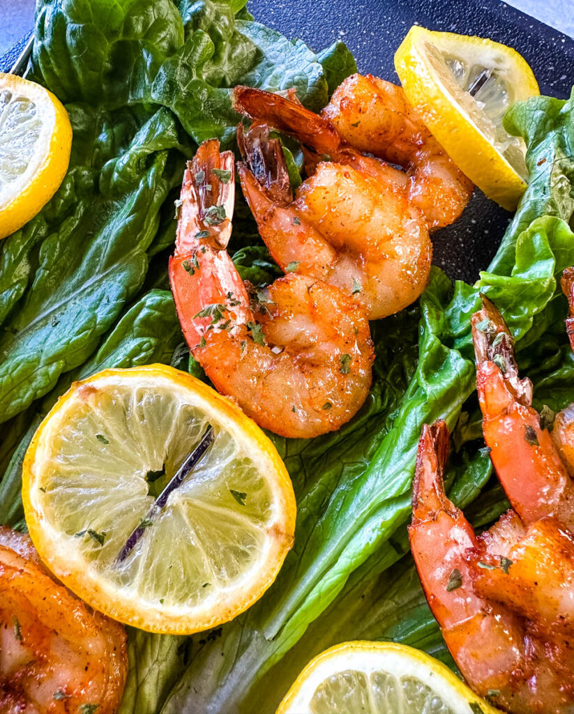 smoked shrimp on skewers with lemon on a bed of lettuce