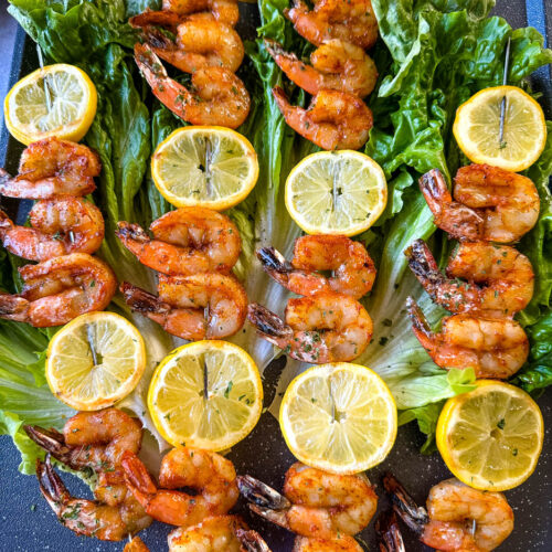smoked shrimp on skewers with lemon on a bed of lettuce