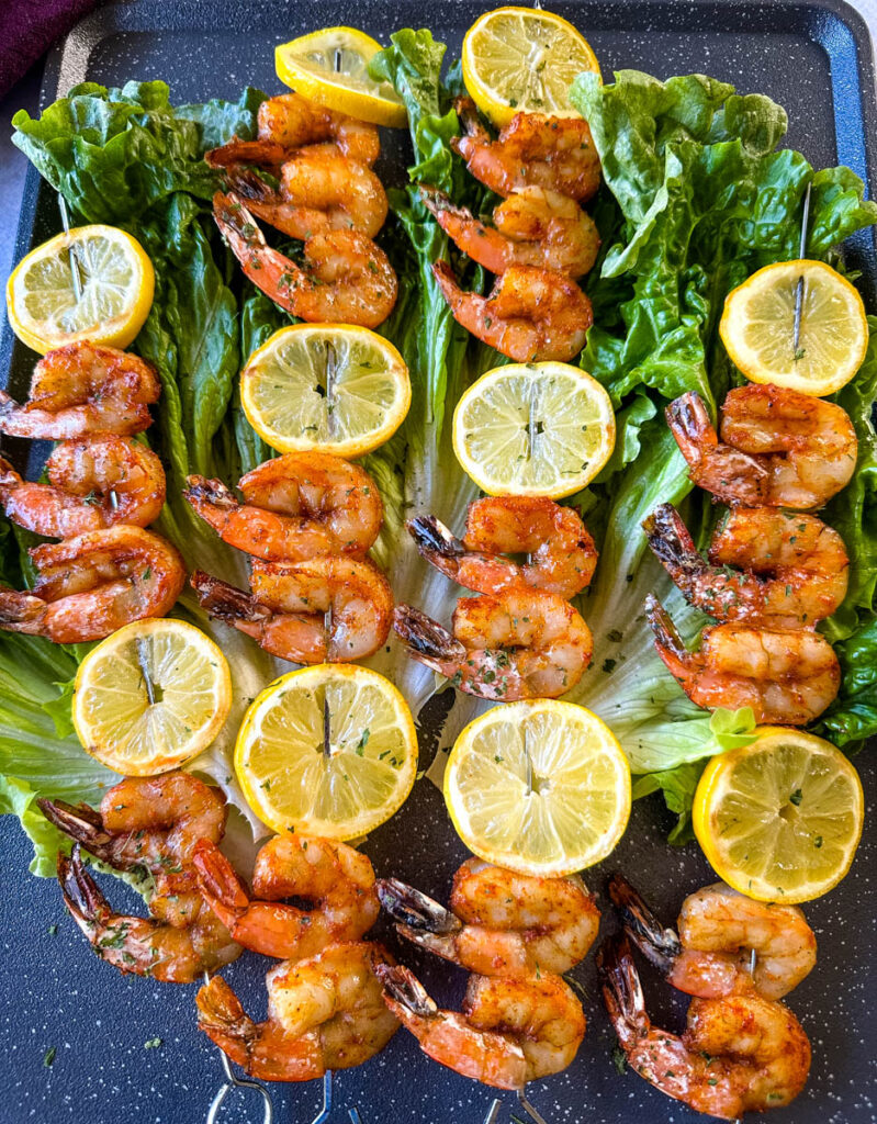 smoked shrimp on skewers with lemon on a bed of lettuce