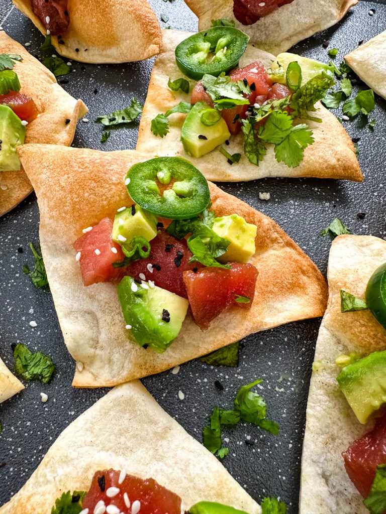 ahi tuna poke sushi nachos on a plate with avocado sesame seeds, jalapenos, and cilantro