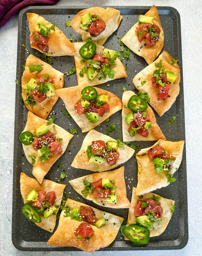 ahi tuna poke sushi nachos on a plate with avocado sesame seeds, jalapenos, and cilantro