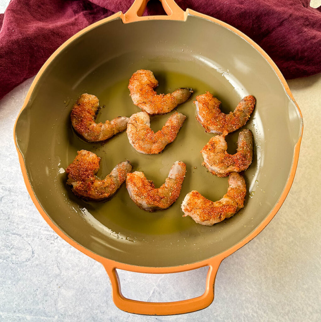 raw shrimp seasoned with Cajun spices in a skillet