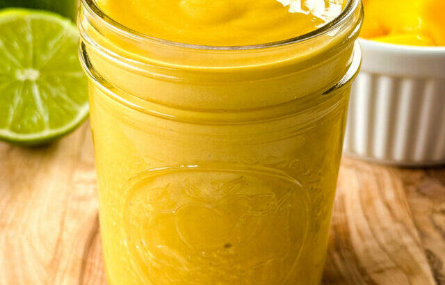 mango salad dressing in a glass jar with fresh lime and fruit