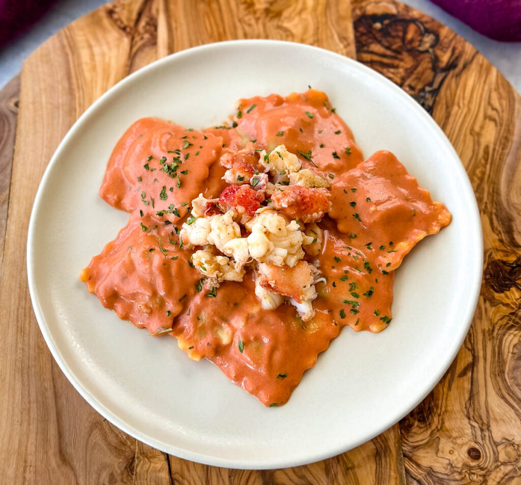 lobster ravioli with tomato cream sauce on a white plate