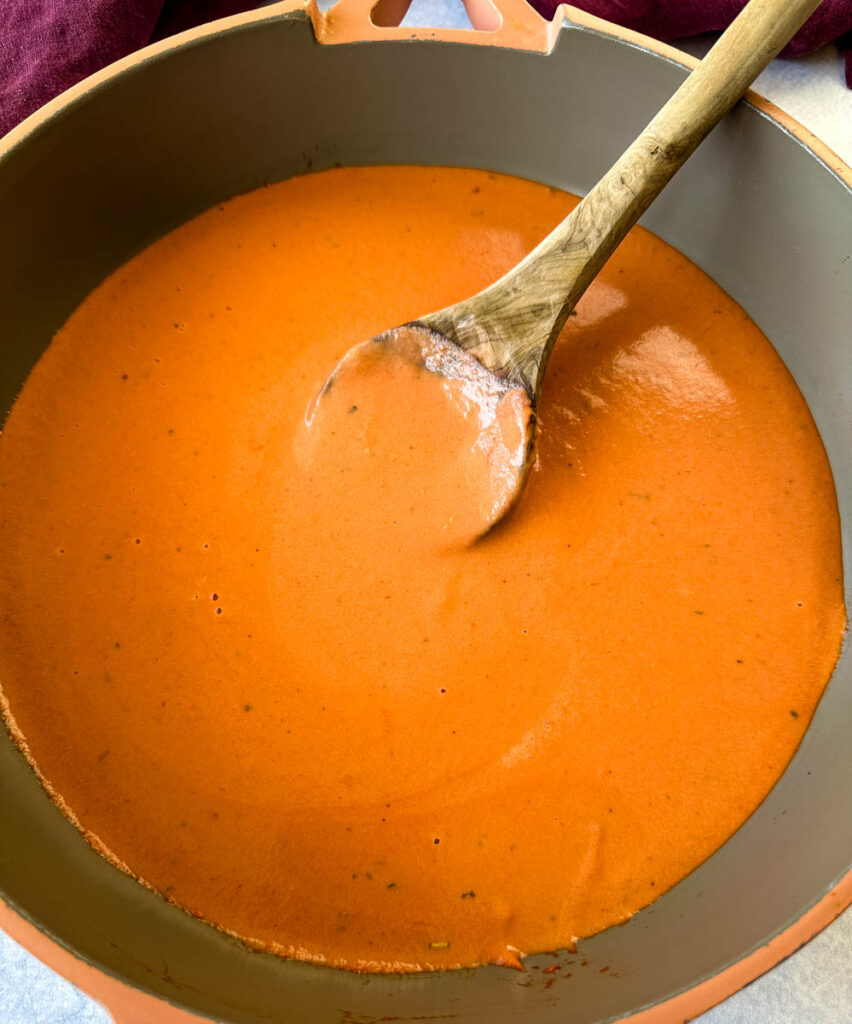 tomato cream sauce in a saucepan with a wooden spoon
