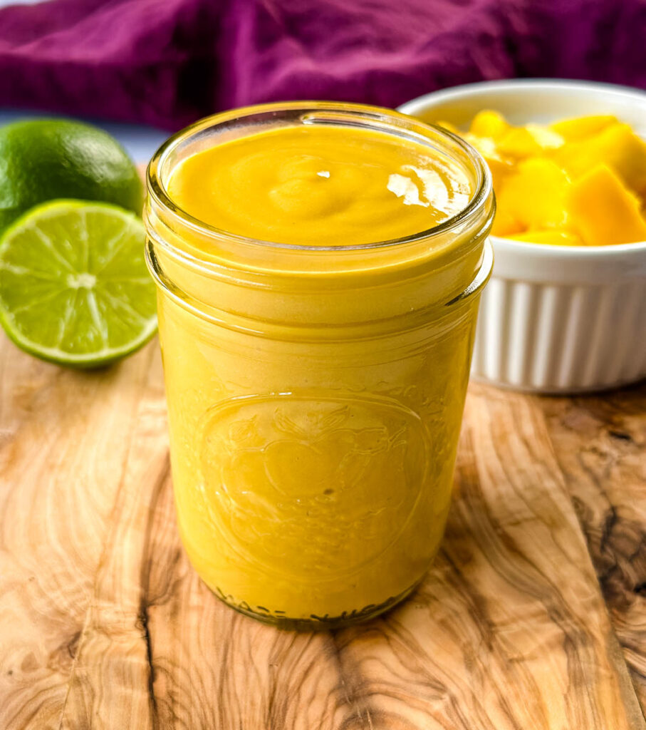 mango salad dressing in a glass jar with fresh lime and fruit