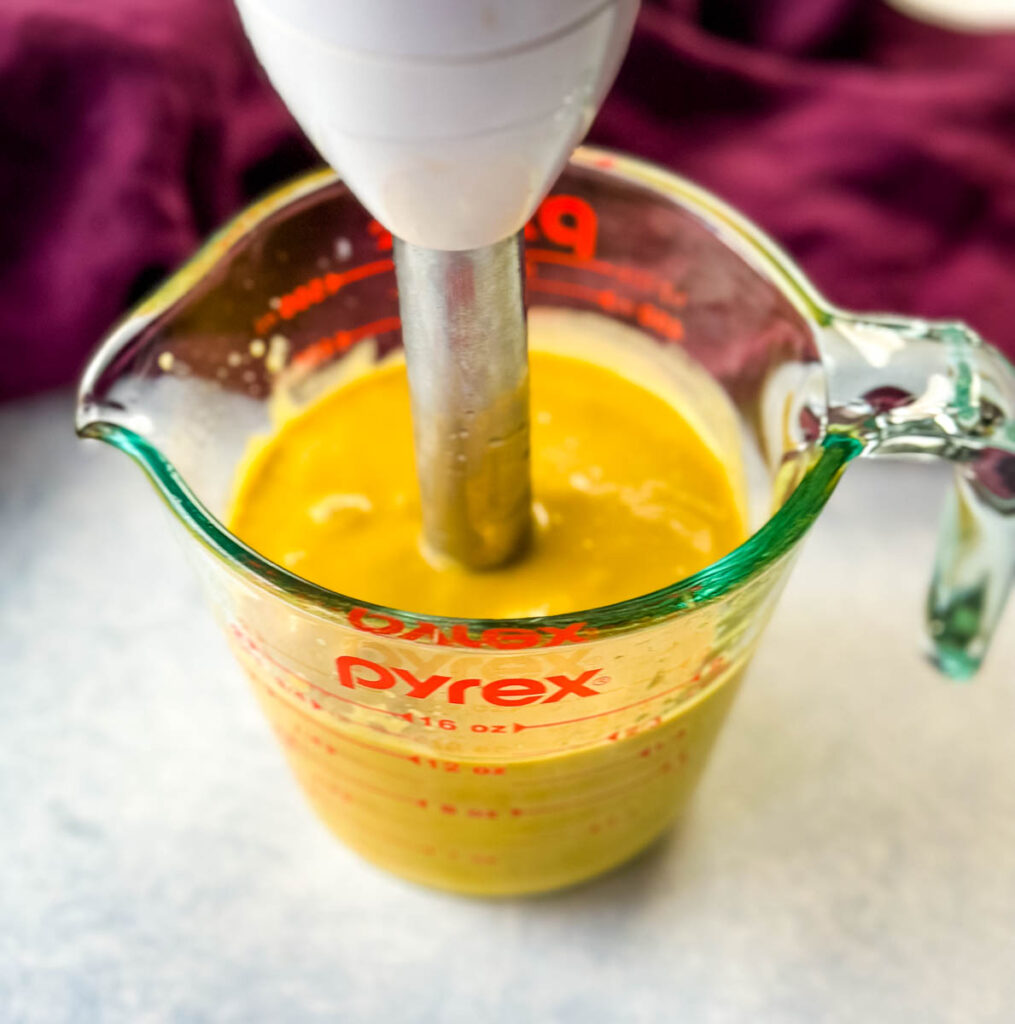 mango salad dressing in a glass jar with an immersion blender