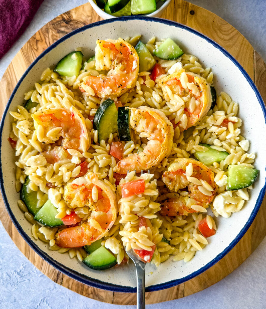 shrimp orzo pasta salad with Italian Dressing and vegetables in a white bowl with a fork