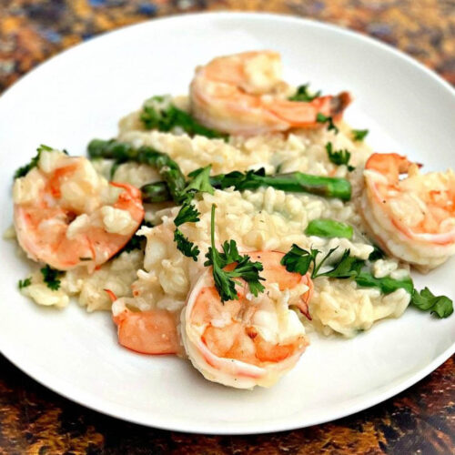 shrimp risotto with asparagus and spinach on a white plate
