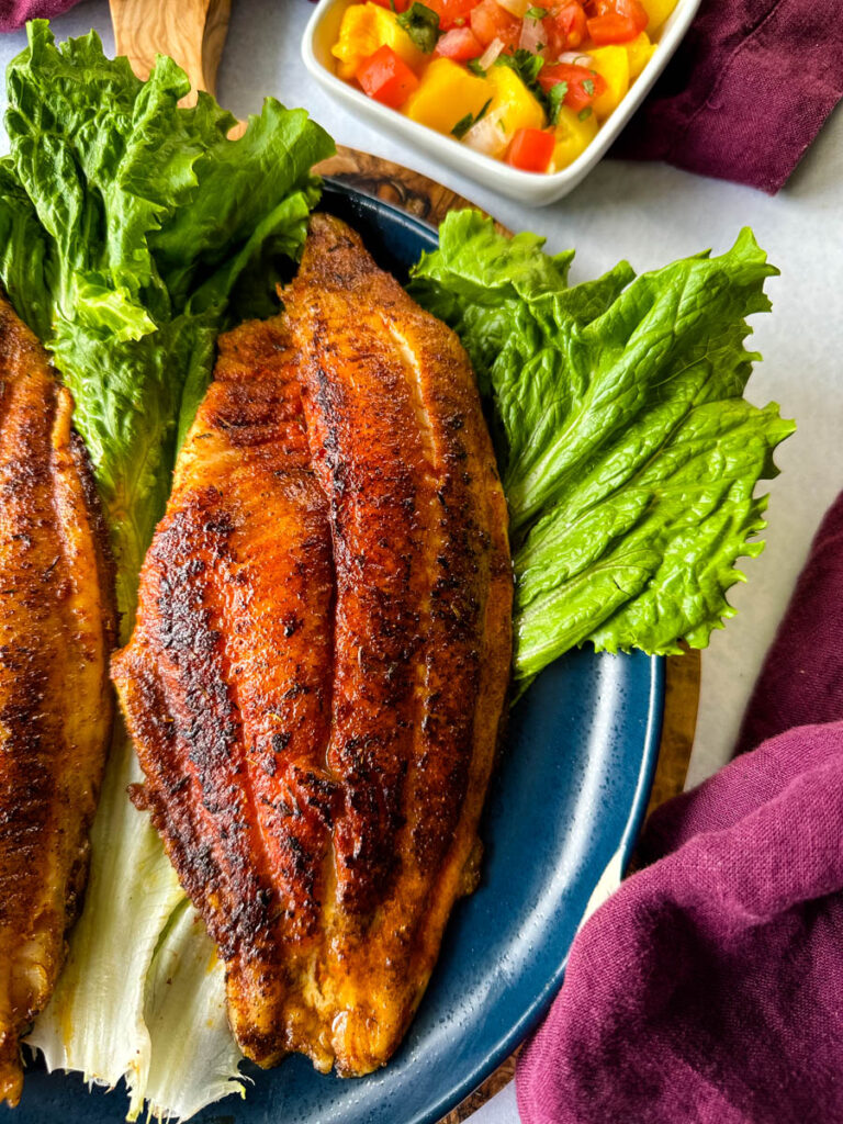 blackened catfish on a plate with lettuce