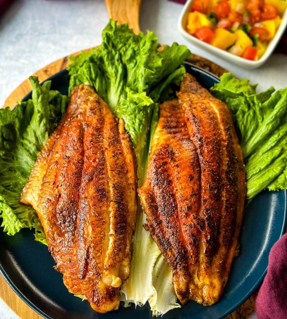 blackened catfish on a plate with lettuce with mango salsa