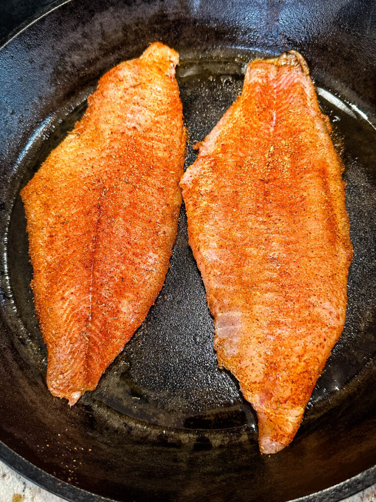 raw seasoned catfish in a cast iron skillet