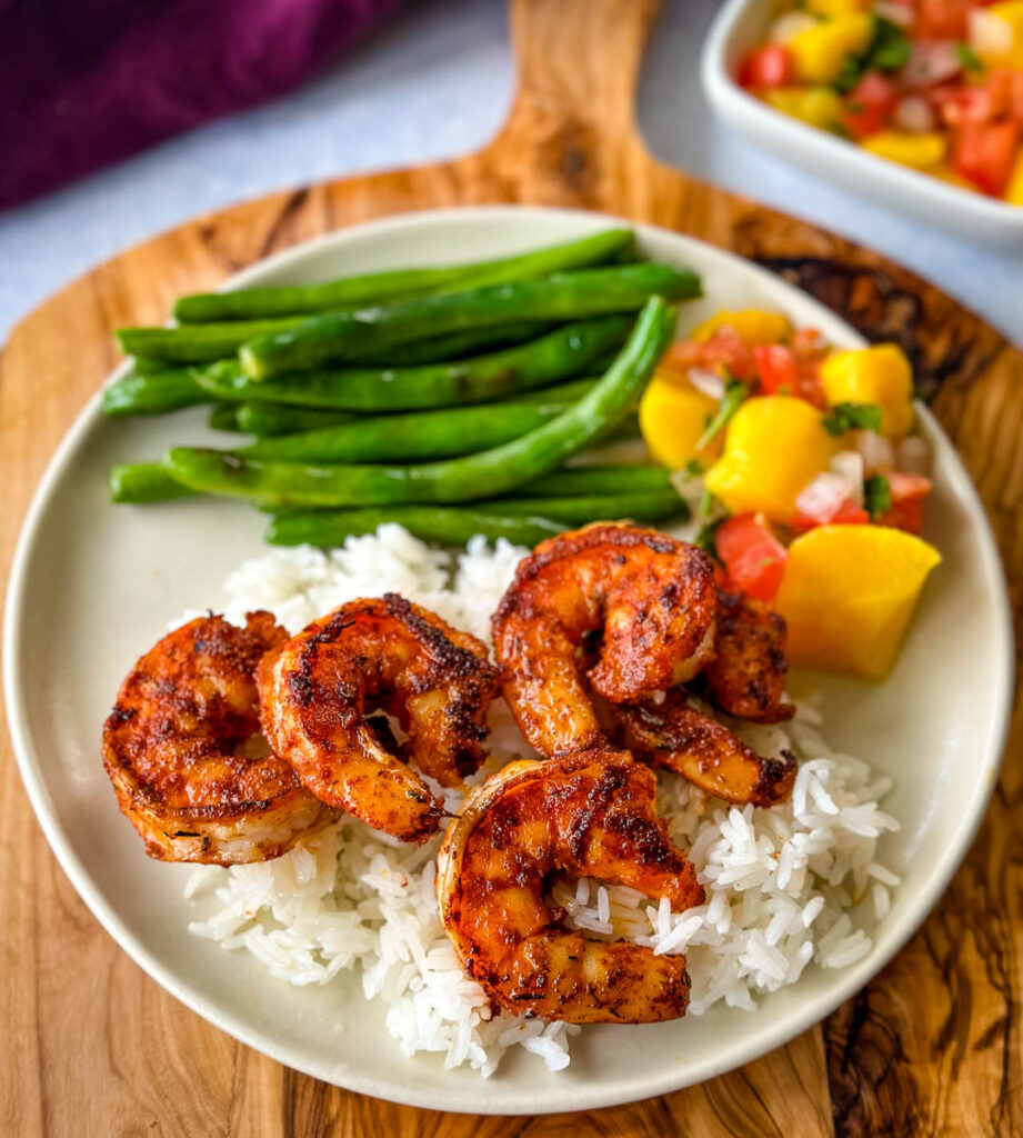 blackened shrimp with rice and green beans on a plate