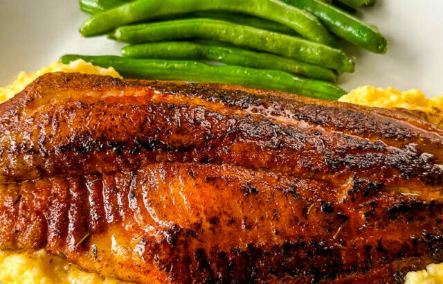 blackened fish on a plate with grits and green beans