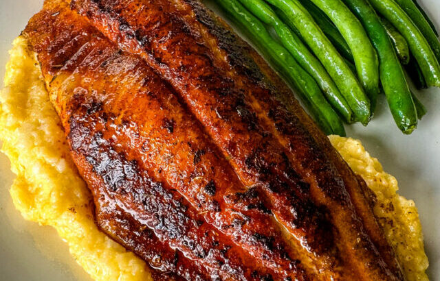 blackened fish on a plate with grits and green beans