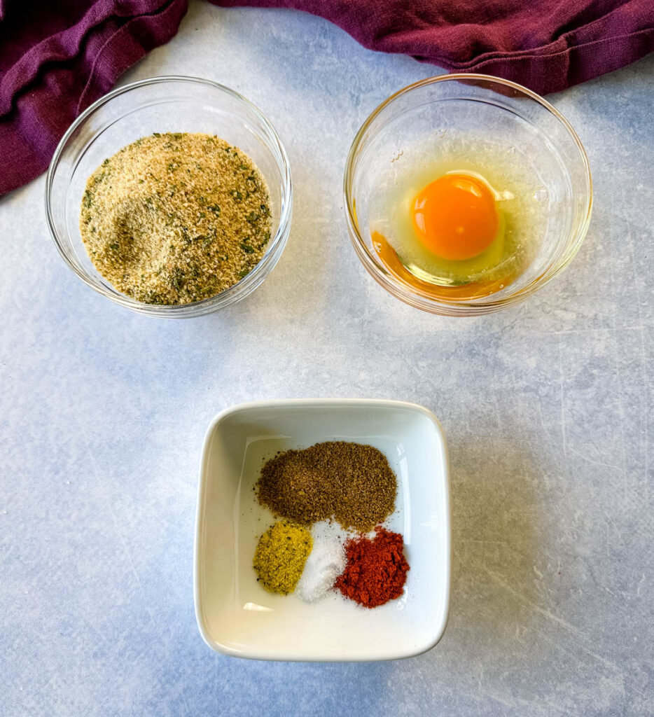raw egg, breadcrumbs, and spices in separate glass bowls