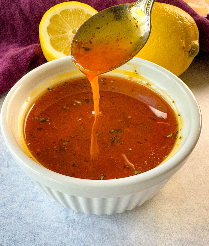 a spoonful of crawfish boil sauce with butter and lemon over a white bowl